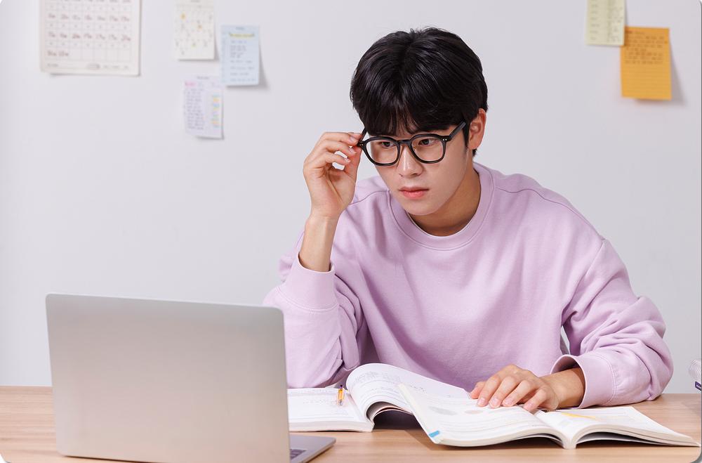 책과 노트북 앞에서 안경을 만지는 모습 · 학부모·학원 선택 참고 사진